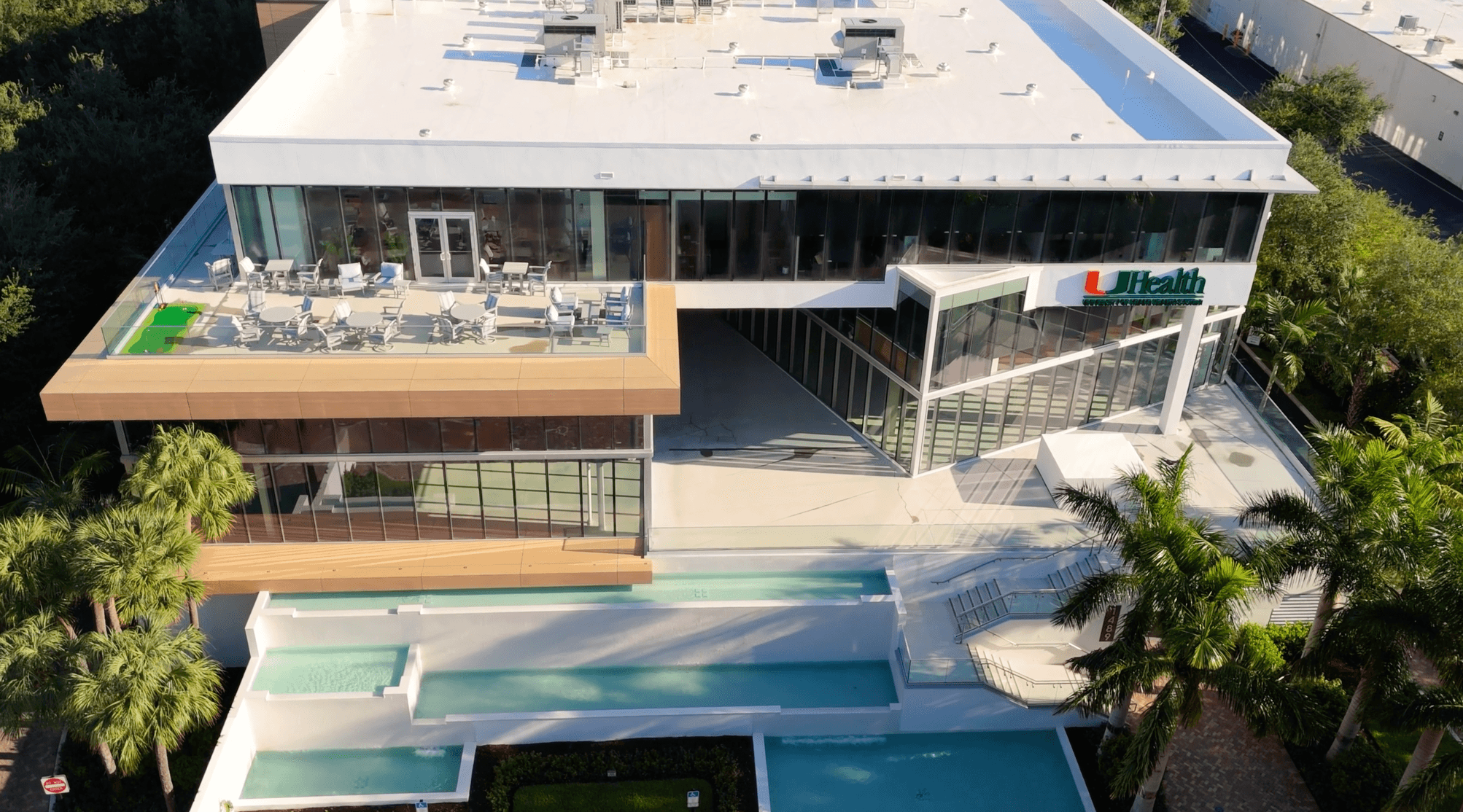 Aerial view of a modern glass office building lined with palm trees in South Florida